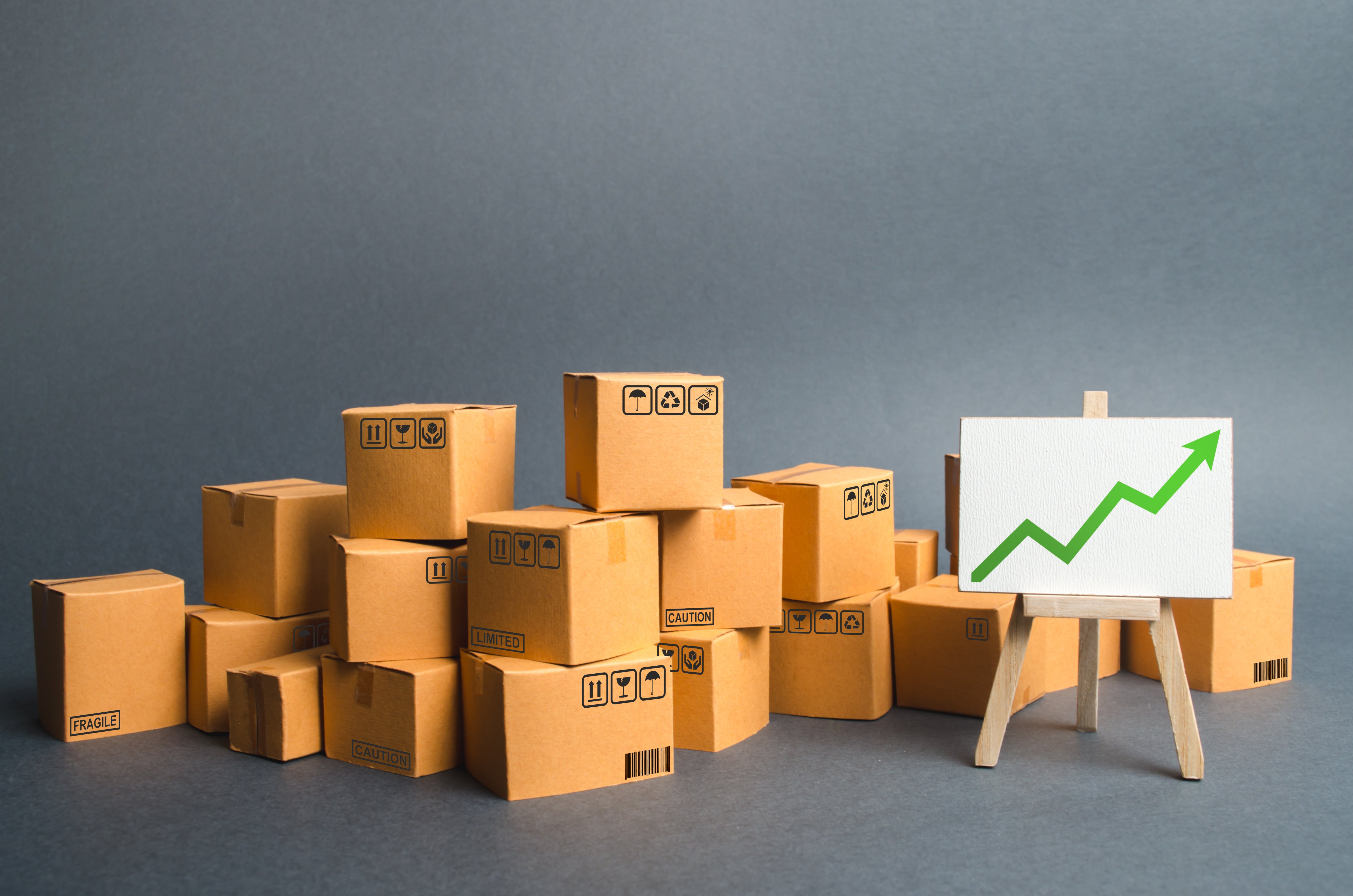 un-monton-de-cajas-de-carton-y-un-soporte-con-una-flecha-verde-hacia-arriba-tasa-de-crecimiento-de-la-produccion-de-bienes